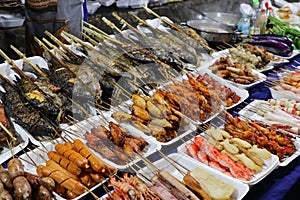 Grilled fish and meat skewers sold in an Asian food street market