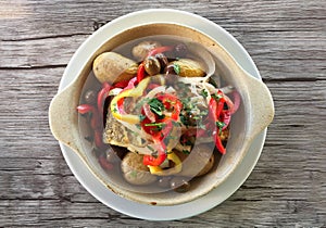 Grilled fish potatoes and olives on wood surface