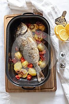 Grilled fish with potatoes and vegetables in a casserole dish