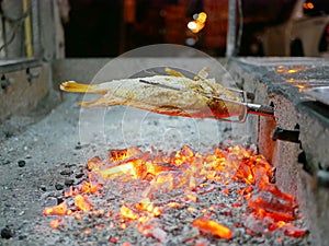 Grilled fish, Red Tilapia, Plaa Tubtim, Pla Pao, and red burning charcoals in a big stove photo