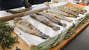 Grilled fish with rosemary. A lot cooked fish with greens on the table at the food festival. Delicious salmon cooked on