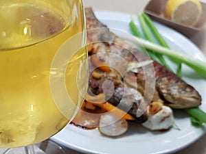 Grilled fish served with white glass of white wine. Gourmet seafood