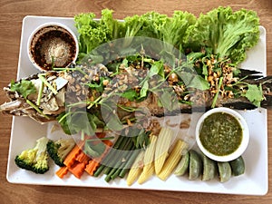 Grilled fish with spicy sauce and vegetable on wood table, Thai food