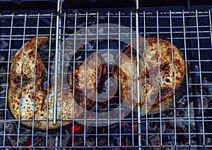 Grilled fish steak. Ð¡ooking  on the grill,  metal fire bowl on the coals in the open air. Barbeque in the garden