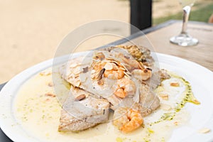 Grilled fish steak with shrimps and almonds on oil