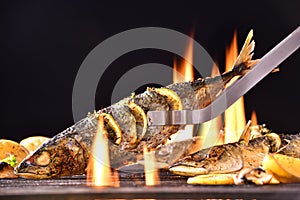 Grilled fish with various vegetables on the flaming grill