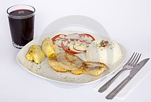 Grilled fish and vegetables, potatoes, rice, tomatoes and a glass of chicha.