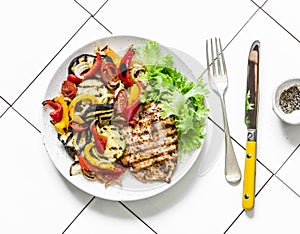 Grilled flounder fillet and roasted vegetables on a light background, top view. Delicious healthy diet food