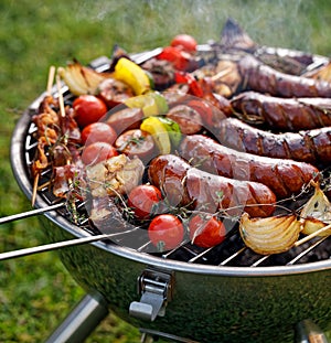 Grilled food. Various grilled products: Grilled sausages, meat and vegetable skewers, bacon and vegetables on the grill plate, out