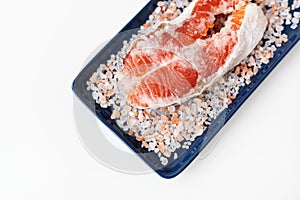 Grilled fresh raw salmon steak with large coarse pink salt. Healthy seafood food