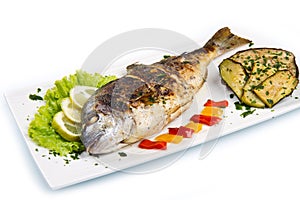 Grilled gilt head sea bream on plate with lemon ,salad and grill