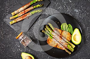 Grilled green asparagus wrapped with bacon and avocado on toasts