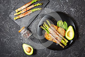 Grilled green asparagus wrapped with bacon and avocado on toasts