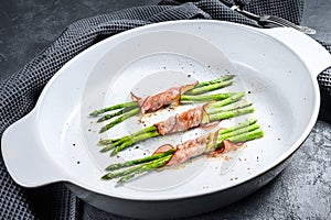 Grilled green asparagus wrapped in bacon. Black background. Top view