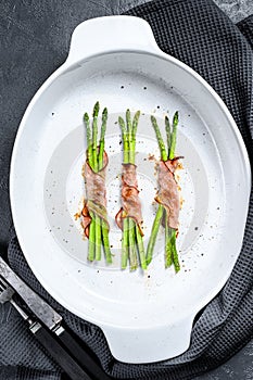 Grilled green asparagus wrapped in bacon. Black background. Top view