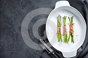 Grilled green asparagus wrapped in bacon. Black background. Top view. Copy space