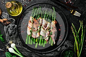 Grilled green asparagus wrapped with bacon. Healthy food. On a stone background.