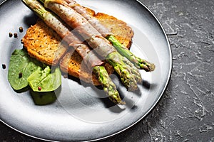 Grilled green asparagus wrapped with bacon on toasts