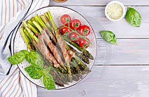 Grilled green asparagus wrapped with bacon on wooden table.