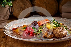 Grilled green vegetables - bell pepper, onion, potatoes, markov and rosemary on a plate. On a wooden table close-up