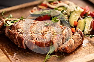 Grilled grilled beef steak with vegetables on wooden board on the table.