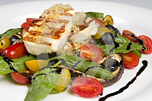 Grilled Halloumi Cheese poured with garlic olive oil salad witch grilled eggplant, cherry tomatoes, black olives and spinach