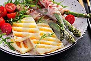 Grilled halloumi cheese salad with tomatoes and asparagus in strips of bacon