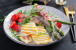 Grilled halloumi cheese salad with tomatoes and asparagus in strips of bacon