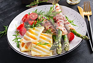 Grilled halloumi cheese salad with tomatoes and asparagus in strips of bacon on plate