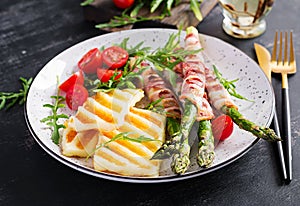 Grilled halloumi cheese salad with tomatoes and asparagus in strips of bacon on plate