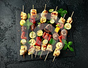 Grilled Halloumi cheese skewers with vegetables on rustic stone board photo