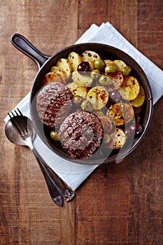 Grilled Hamburgers with Potatoes served in a Ceramic Dish