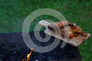 Grilled hot grilled chicken thighs on a grill on a wooden board with smoke around. outdoors. Free space for text