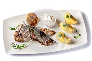 Grilled juicy mackerel, served with mashed potatoes, lemon, and tartar sauce. Microgreen. Modern pitch on a white tarekle