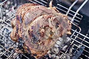 Grilled juicy pork knuckle. Appetizing knuckle or boar hoof. Cooking pork leg on coals. Close-up. Selective focus