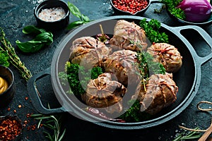 Grilled Juicy Turkey Cutlets. In a pan with spices and herbs. On a black stone background.