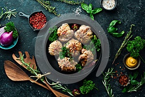 Grilled Juicy Turkey Cutlets. In a pan with spices and herbs. On a black stone background.