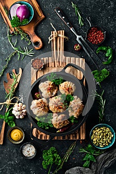 Grilled Juicy Turkey Cutlets. In a pan with spices and herbs. On a black stone background.