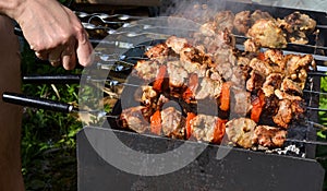 Grilled kebab cooking on metal skewer closeup. Roasted meat cooked at barbecue. Traditional eastern dish, shish kebab. Grill on ch