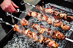 Grilled kebab cooking on metal skewer. Roasted meat cooked at barbecue. Traditional eastern dish, shish kebab. Grill on