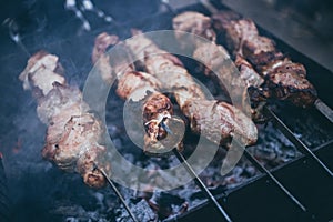 Grilled kebab cooking on metal skewers grill.