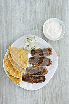 Grilled kebabs with pita bread, chopped onion and yogurt sauce