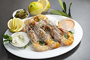 Grilled King prawns or shrimps with parsley on white plate on dark rustic background