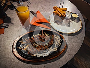 Grilled lamb ribs with french fries and orange juice on a plate photo