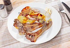 Grilled lamb ribs with golden crust served with fried potatoes. Traditional spanish dish cordero ribs photo