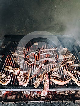 Grilled lamb ribs. Large metal grate with hot coals.