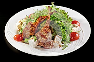 Grilled lamb ribs with onion, salad and sliced tomato