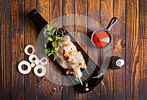 Grilled Lula kebab on skewers with spices in a black plate on a wooden background