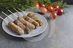 Grilled lule kebab on grey plate,fresh tomatoes,bunch of dill on dark kitchen table.Free space for text photo