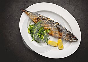 Grilled mackerel fillets with lemon on black board